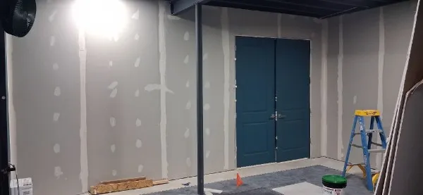 A wider view of the finished basement walls and the double doors