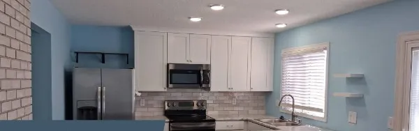 The finished kitchen with white shaker cabinets, a subway backsplash, stone counters and a peninsula